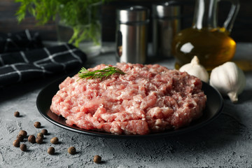 Spices and plate with minced meat on grey background, close up