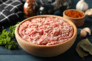 Spices and bowl with minced meat on wooden background, close up