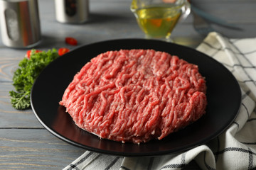 Spices and plate with minced meat on wooden background, close up
