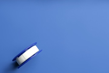 Sticking plaster roll on blue background, top view. Space for text
