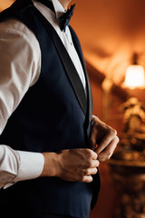 A man fastens with a cufflink on the cuff of the sleeve of a luxurious white shirt. Close up of a man hand wearing a white shirt and cufflinks. Captures the groom cufflinks.