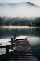 Wooden pier and boats. Morning fog over the Saint Anne  Lake. Majestic autumn background.