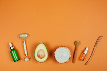 Natural face care cosmetics with ingredients on peach background. Flat lay style.