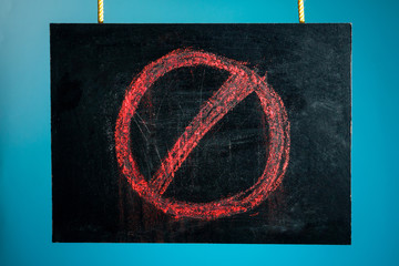 Chalk board is suspended with a pattern of a red prohibition sign on a blue background. copy space