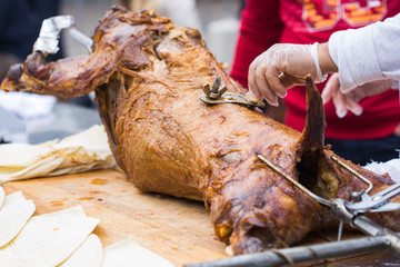 Cutting the mutton hulk fried on a grill for the pilaf. Male hands keep a knife in gloves and cut meat