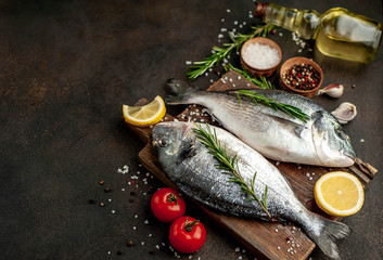 Fresh dorado fish with spices and ingredients tomato, razmorin, sunflower oil, lemon for cooking on a stone background with copy space for your text