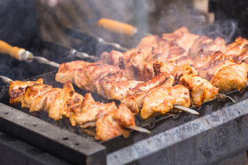 Delicious bbq kebab grilling on open grill, outdoor kitchen. Food festival in city. Tasty food roasting on skewers, food-court. Summer picnic