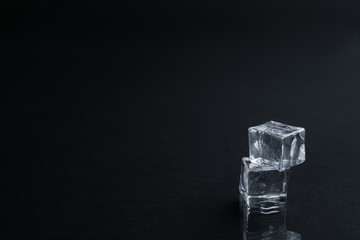Crystal clear ice cubes on black background. Space for text