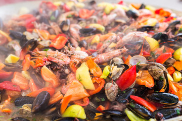 Street food concept - Gourmet seafood paella with pink marine prawns and mussels on yellow saffron rice with peas and bell peppers