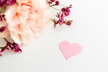 bouquet of flowers on the white background with pink paper heart symbol of love