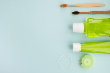 Bamboo toothbrushes and oral hygiene products on light blue background. Dental hygiene concept. Top view, flat lay, copy space