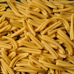 Closeup image of raw italian casarecce pasta. Flatlay with raw uncooked pasta on dark background. Italian cuisine