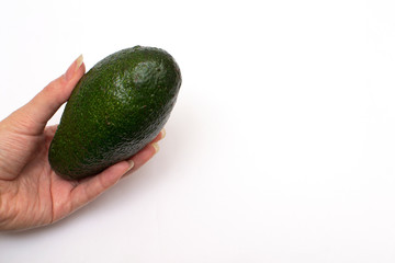 one ripe avocado in a female hand on a white background with a place for writing