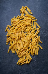 Raw italian casarecce pasta. Flatlay with raw uncooked pasta on dark background. Italian cuisine