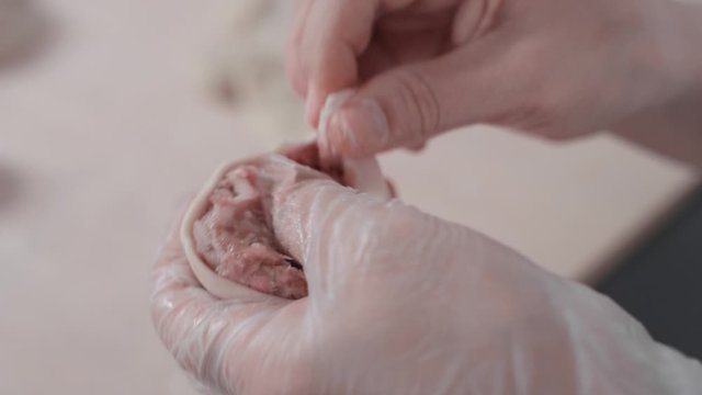 Close-up: a woman's hands cooks a delicious buuz (Manty) with her hands and puts it on the table. The process of modeling buuz cook. Traditional Mongolian cuisine, meat and dough dishes. 4K, Red Epic
