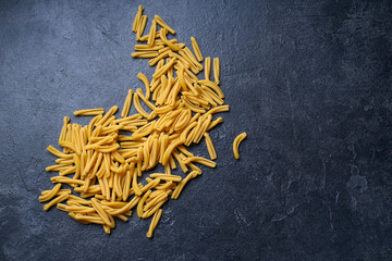 Raw italian casarecce pasta. Flatlay with raw uncooked pasta on dark background with copy space. Italian cuisine