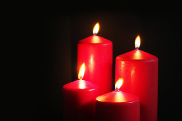 Fototapeta na wymiar Red burning candles on a black background