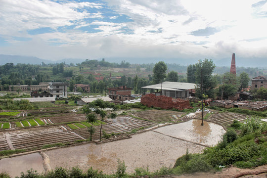 A rural village in Nepal near Kathmandu valley in the district of Banepa with paddy fields and houses in between in a sunny day.