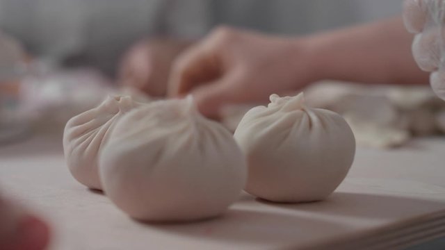 Close-up: a woman's hand puts a delicious buuz (Manty) on the table. The process of modeling buuz cook. Traditional Mongolian cuisine,dishes made of meat and dough with your own hands. 4K, Red Epic