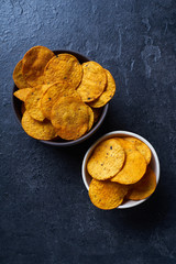  Mexican round-shaped nacho chips in two bowls. Top view chips on dark background with copy space
