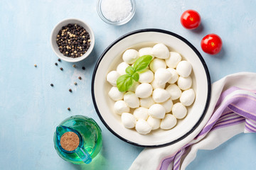 Mini mozzarella cheese in iron plate on blue concrete background. Top view.
