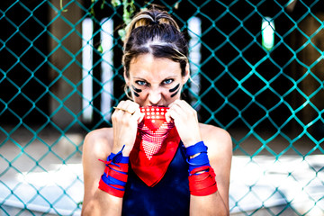 Close up on a young angry activist blond hair woman putting her red bandana on her face, looking at...