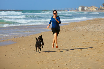 Mature Woman  playing with her dog on the beach.