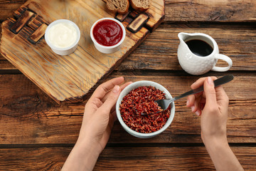 Woman eating tasty brown rice at wooden table, top view