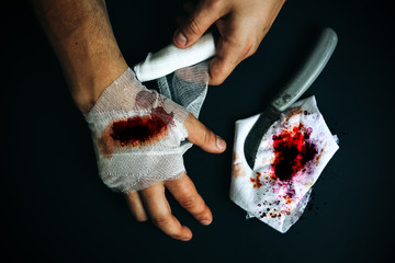 Man is putting the bandage on the wound. Bleeding injury. Deep cut with a knife.