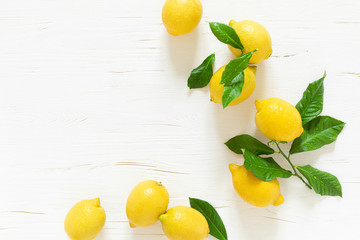 Fresh lemons with leaves on white wooden background,  summer lemonade ingredient, vitamin c concept, top view.
