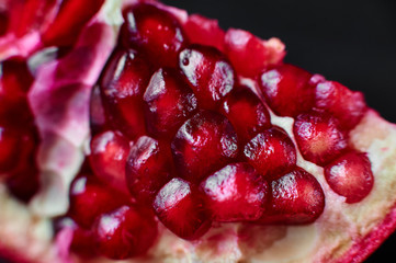 red pomegranate on a black wooden background, food shot