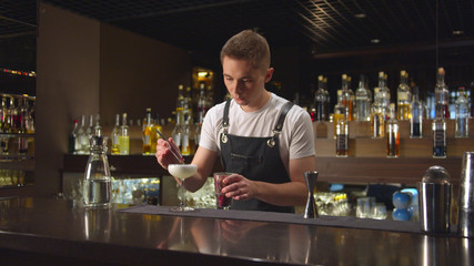 Bartender puts berries with tongs in glass with alcohol at the bar