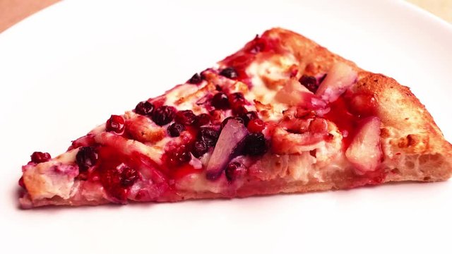 Close-up of tasty pizza slice with pineapple and cowberry in clean white plate