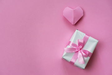 Pink Valentine's background with a gift box and origami heart, copy space on left side.