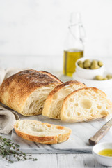 Italian ciabatta bread with olive oil, thyme and olives on a marble board.  Sliced ciabatta....