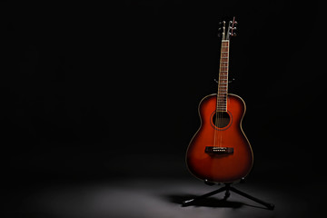 Folk style parlor acoustic guitar in darkness on black background with a lot of copy space for...