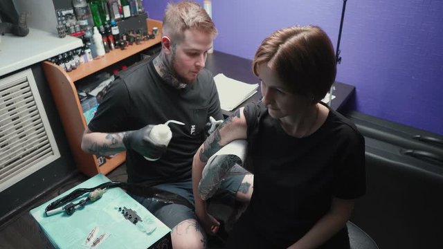 Footage of young master getting tattoo of snake in salon, top view