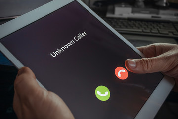 Unknown caller. A man holds a tablet in his hand and thinks to end the call. Incoming from an unknown number at night. Incognito or anonymous