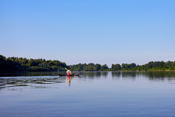 Fototapeta na wymiar Rear view of man paddling the wooden kayak in the lake or river