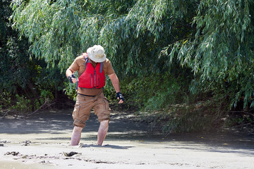 Man standing in natural quicksand river, clay sediments, sinking, drowning quick sand, stuck in the soil - obrazy, fototapety, plakaty
