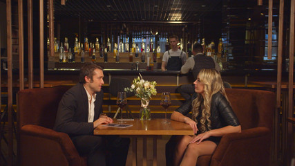 Man and woman sit in a cafe,talk and flirt with each other