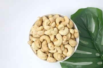 Cashews are in a cup and have leaves.