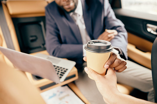 Close Up Of A Coffee Cup Being Held By A Man On Back Car Seat.