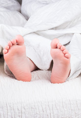 Feet of cute little children lying in bed
