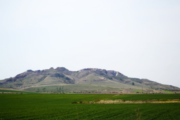 Obraz premium Landscape of a mountain in the back of a green field and clear sky