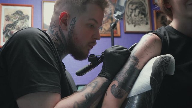 Video of man doing black tattoo of snake for woman in studio