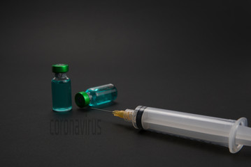 Green liquid vials and syringe on black background. Medical health concept.