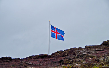 Icelandic national banner or flag of Iceland with rocks and grey sky