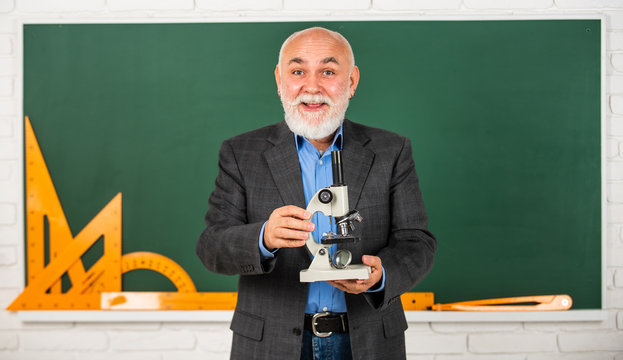 happy senior teacher use microscope. chemistry in school laboratory. science experiments with microscope in lab. Biology school laboratory equipment. man in classroom with math tools at blackboard - Powered by Adobe