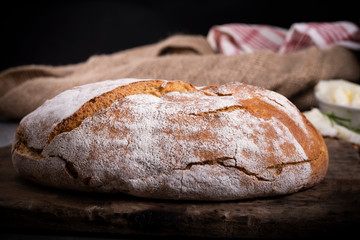 The farmhouse loaf of bread. The sourdough bread on a wooden cutting board.